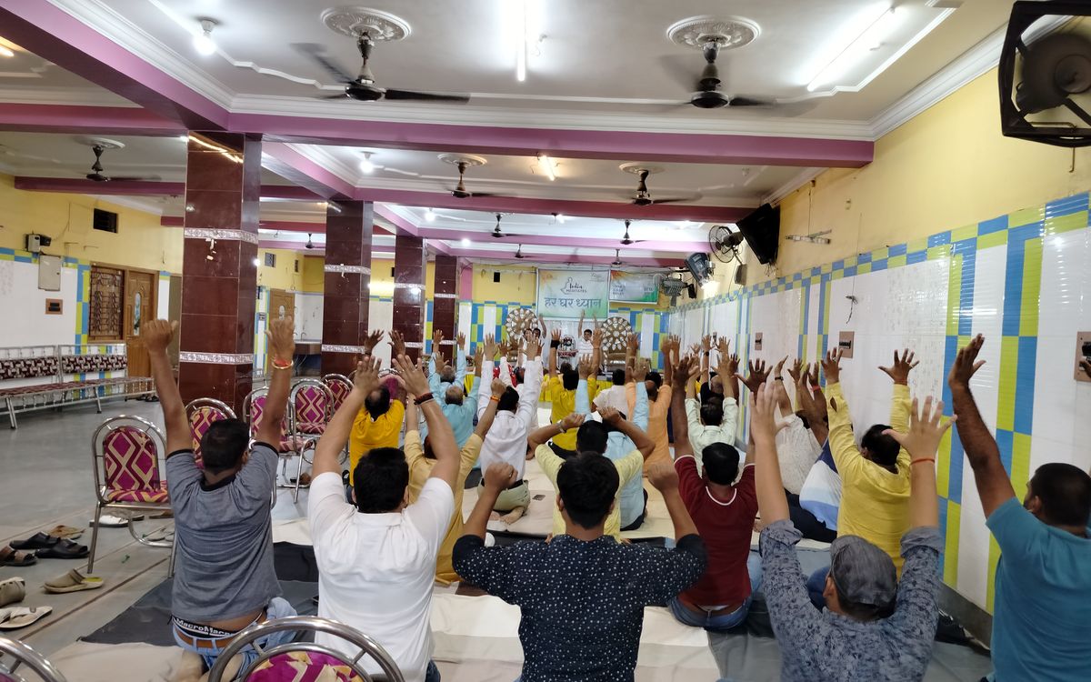 हर घर ध्यान कार्यक्रम में एक साथ ध्यान करते लोगों से भरा हॉल